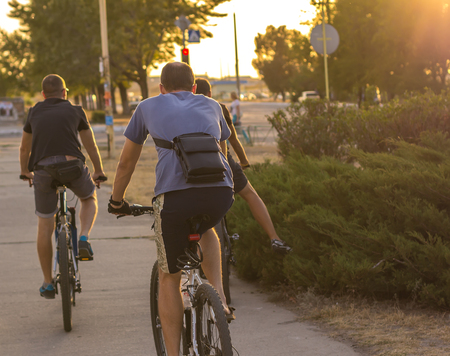 three sport Man riding a bike in the city at sunsetの写真素材