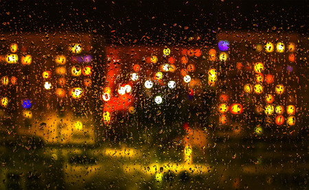 Raindrops on the window with night blurred lights outside the windowの写真素材