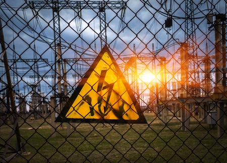 sign "dangerous voltage" on the background of power plant at sunset.の写真素材