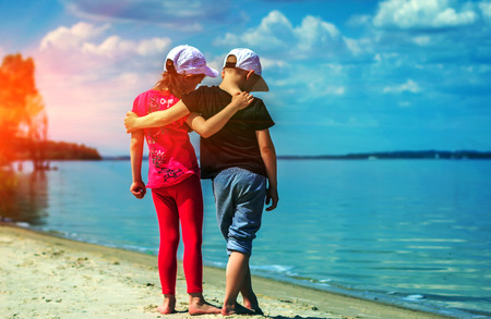 first love. boy with the girl in an embrace on the beach at sunset in the sand.の写真素材
