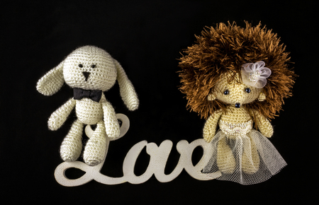 toy braided newlyweds, the bride and groom on a black background. wedding symbols with the word love.の写真素材