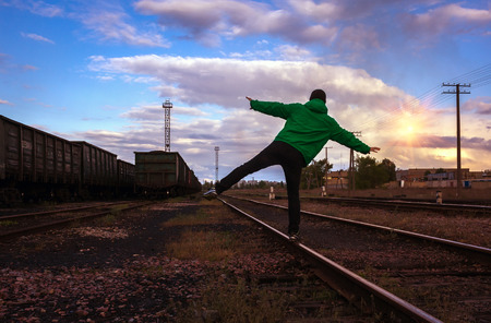 man travels on rails, against the background of beautiful clouds at sunsetの写真素材