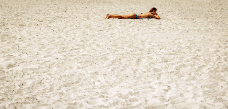slender woman sunbathing on beach in bikiniの写真素材