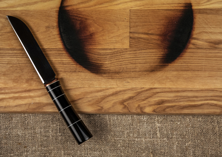 Steel kitchen knife on a wooden board and rough fabricの写真素材