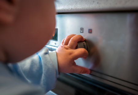 dangerous situation, the child is playing with an electric stove. The child plays near a hot stove.の写真素材