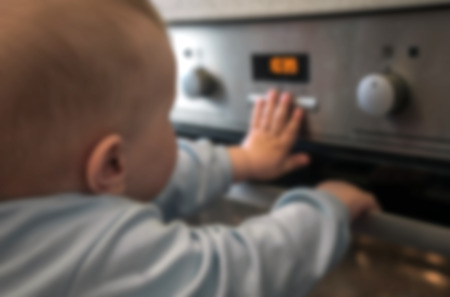 dangerous situation, the child is playing with an electric stove. The child plays near a hot stove.の写真素材
