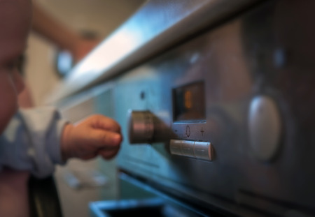 dangerous situation, the child is playing with an electric stove. The child plays near a hot stove.の写真素材
