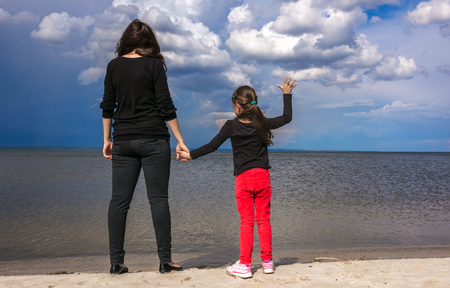 young mother with her daughter on the beach at sunsetの写真素材