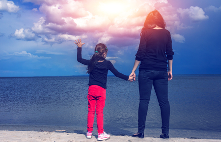 young mother with her daughter on the beach at sunsetの写真素材
