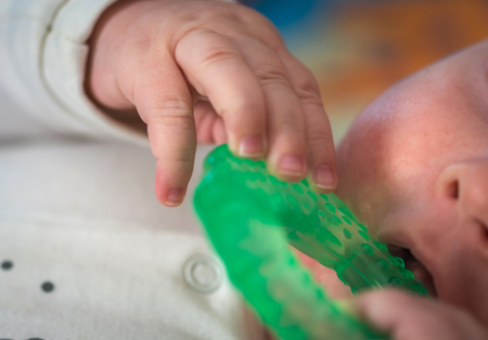 teething, the first tooth in a child. the child gnaws a toy.の写真素材