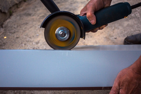 builder cuts a metal structure with a lot of spindles by a grinding machine.