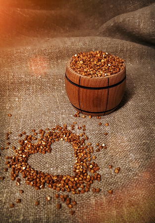 grains of buckwheat at sunset, drawing of a heart on burlap, rural background. Organic, diet food.の写真素材
