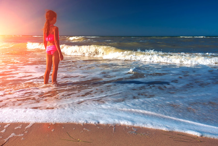 Nice girl meditating by the ocean at sunset. Beautiful girl teenager relax.の写真素材
