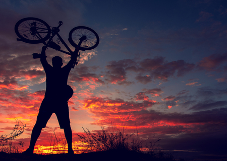 cyclist on the mountain with a bicycle, admiring the fiery sunset.の写真素材