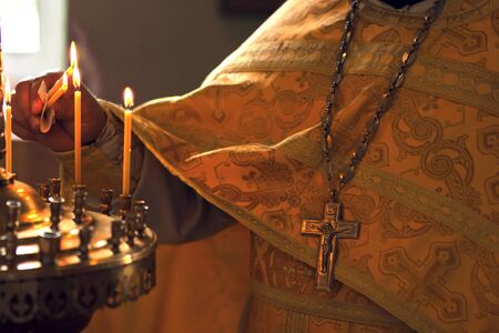 burning candle in his hand, a prayer in the church. The Christian faith.
