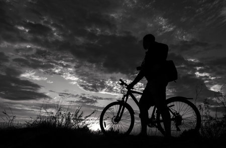 cyclist on the mountain with a bicycle, admiring the fiery sunset.の写真素材