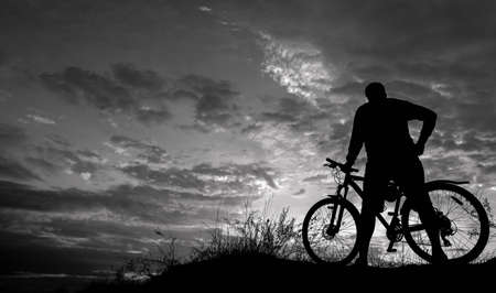 cyclist on the mountain with a bicycle, admiring the fiery sunset.の写真素材