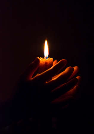 burning candle in his hand, a prayer in the church. The Christian faith.の写真素材