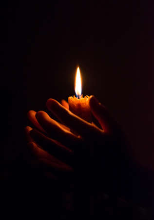 burning candle in his hand, a prayer in the church. The Christian faith.の写真素材