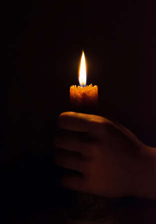 burning candle in his hand, a prayer in the church. The Christian faith.の写真素材
