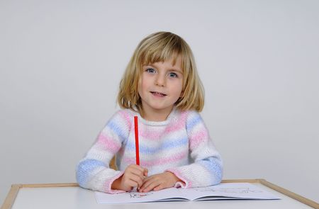 little girl paint a picture with red crayonの写真素材