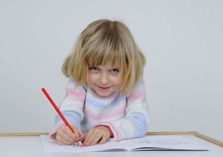 little girl paint a picture with red crayonの写真素材