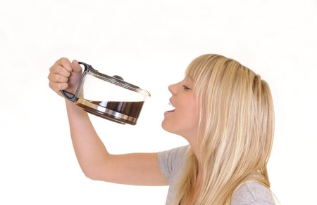 young blond woman in front of white background drinking coffee from a jugの写真素材