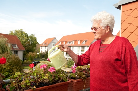 old woman watering flowers on the balcony