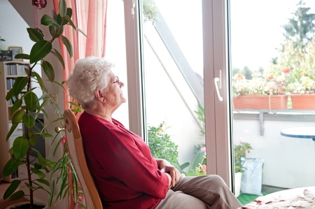 lonely old woman looks out the windowの写真素材