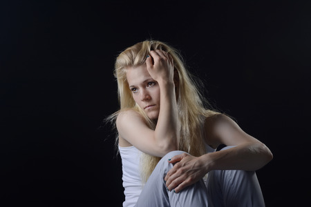unhappy young woman in front of black backgroundの写真素材