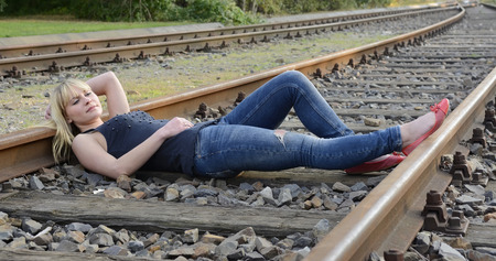 beautiful young woman lying on rail trackの写真素材