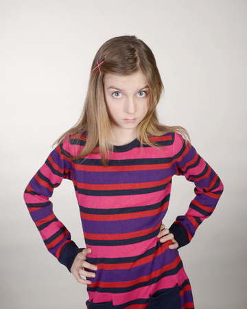 sceptical little girl against grey backgroundの写真素材