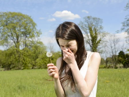 young woman sneezes on a flower meadowの写真素材