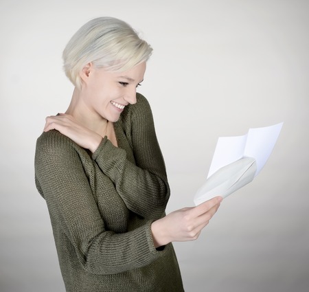 happy young woman reading letter, gray backgroundの写真素材