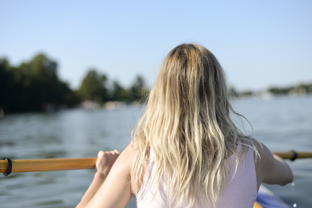 young blond woman in boat, rear viewの写真素材