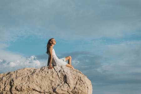 young girl sitting on rockの写真素材