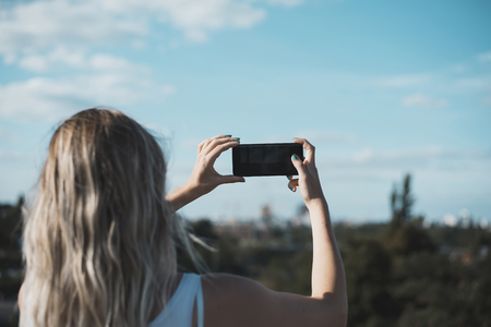 young woman photographing with smartphoneの写真素材