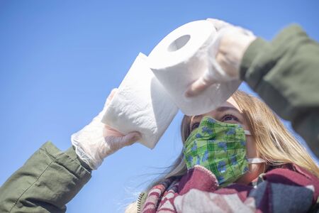 young woman with mask and toilet paper in the city