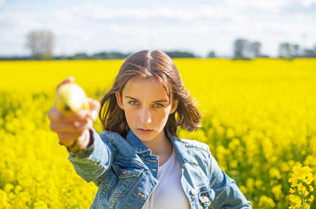 young girl with banana standing in rape field