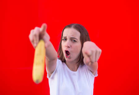 happy young girl with banana against red background