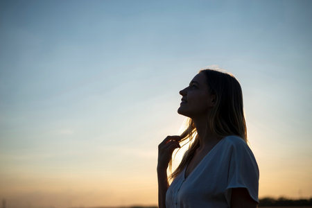 happy young blond woman enjoying sunsetの写真素材