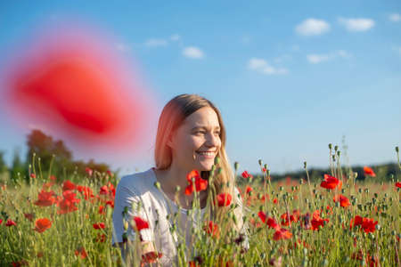 pretty young woman enjoying sun in poppy fieldの写真素材