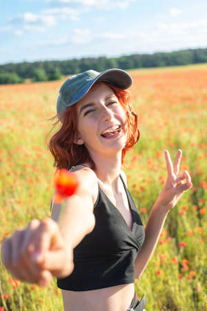 happy young girl with poppy flower showing victory sign