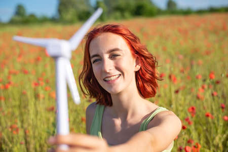 girl with wind turbine in poppy fieldの写真素材