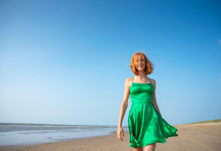 happy young girl in green dress on the beachの写真素材