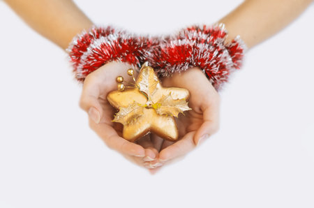 A golden Christmas star in the hands of a young girl. The hands of a young girl are decorated with a red decorative Christmas garland on a white background. Happy Christmas Ever. Chの写真素材