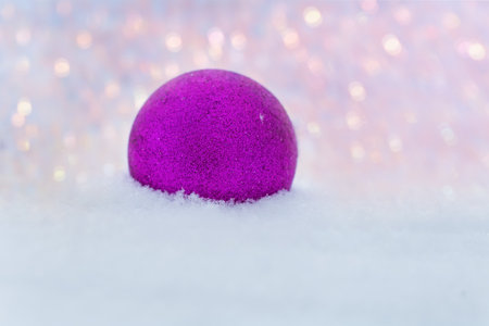A pink New Year ball lies on the sparkling snow outdoors on a frosty winter day. christmas toys. Space for text. Christmas, festive design.The concept of Christmas and New Year.の写真素材