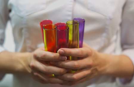 Close-up of female hands holding test tubes with multicolored liquidsの写真素材