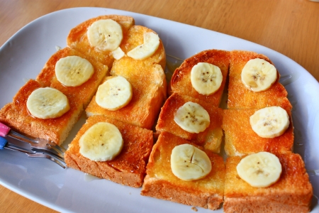 bread toast with honey and banana on plateの写真素材