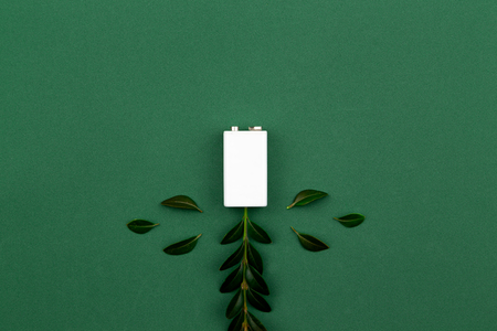 charging Eco energy or green power illustration with a white battery and sprigs leaves on a green background with copy space for text.の写真素材